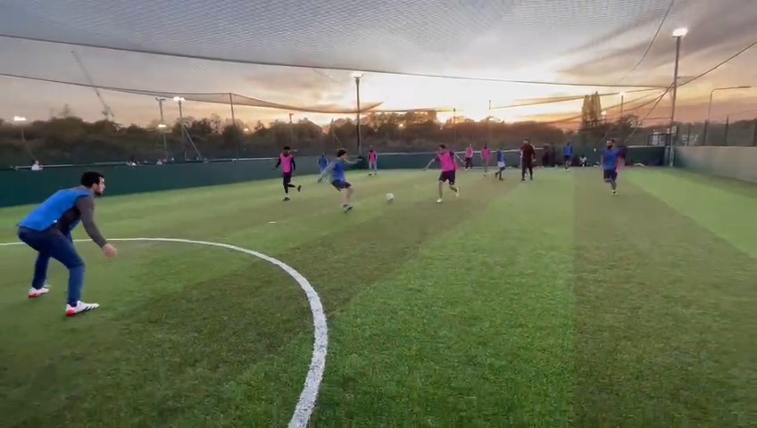 a team of footballer are playing with a sunset at the back