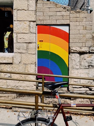 a rainbow flag on the wall with a bike locked 