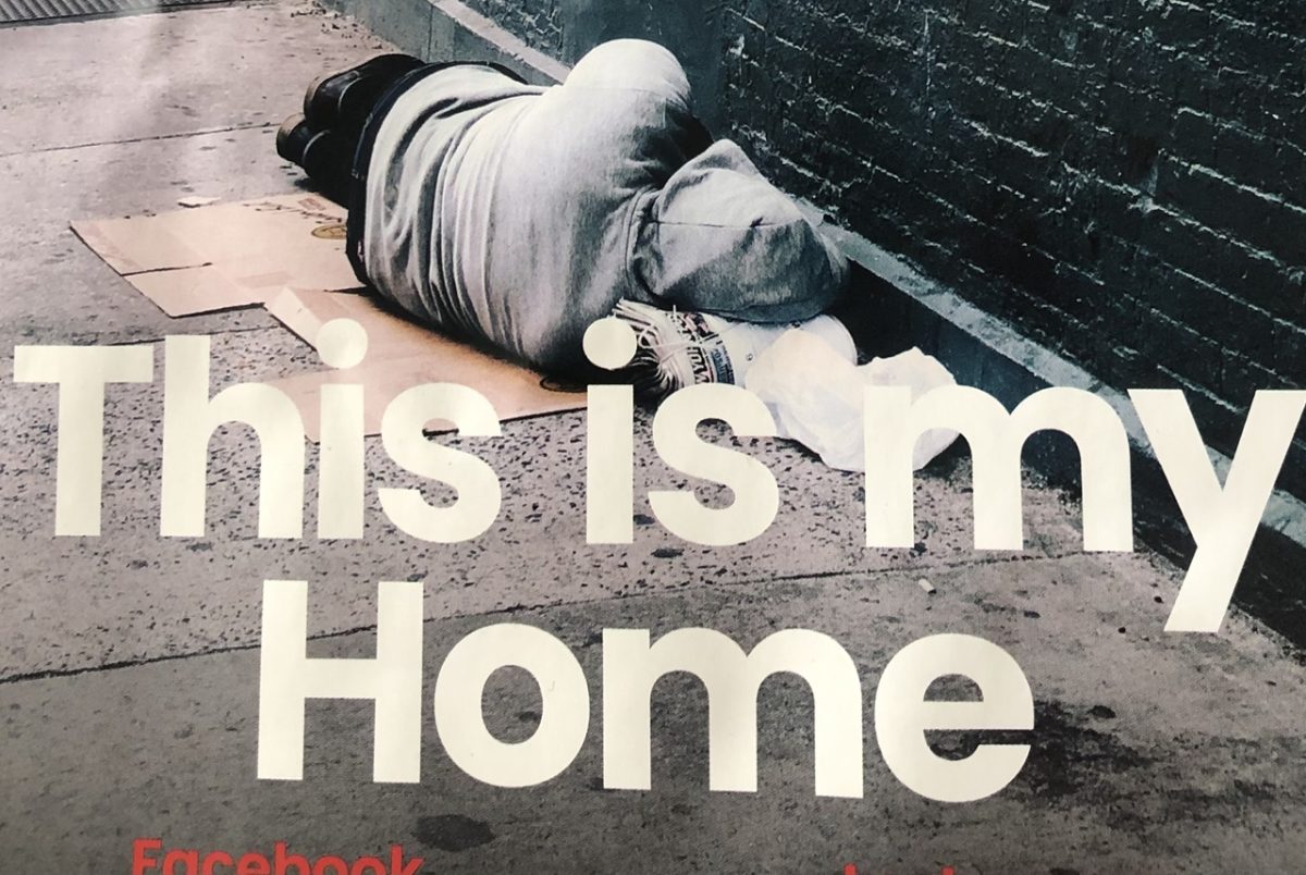 a close up photo of a homeless person sleeping on the pavement. "this is my home" is written in overlay over the image.